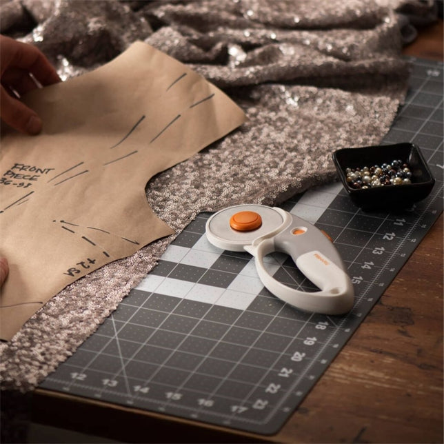 Fabric cutting tool with pattern paper and rotary cutter on a cutting mat