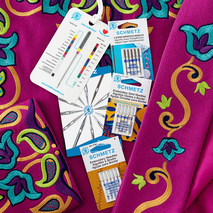 Schmetz machine embroidery needles bundle and fabric with colorful patterns on a pink background