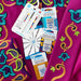 Schmetz machine embroidery needles bundle and fabric with colorful patterns on a pink background
