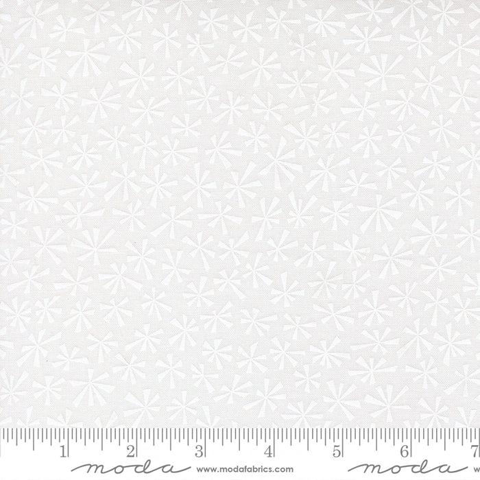 Snow Time Winter White on White Tinsel fabric shown beside a ruler to display the print scale and repeat width
