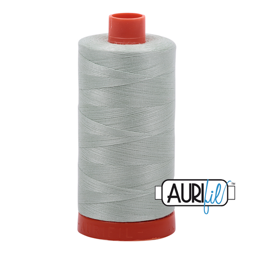 A spool of Aurifil 50wt platinum thread with a grey hue and red cap.