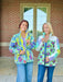 Two women wearing colorful jackets standing in front of a brick building. Bella Quilt Coat pattern 