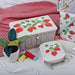 Embroidered strawberry designs on fabric pieces with a red and white checkered cloth in the background.