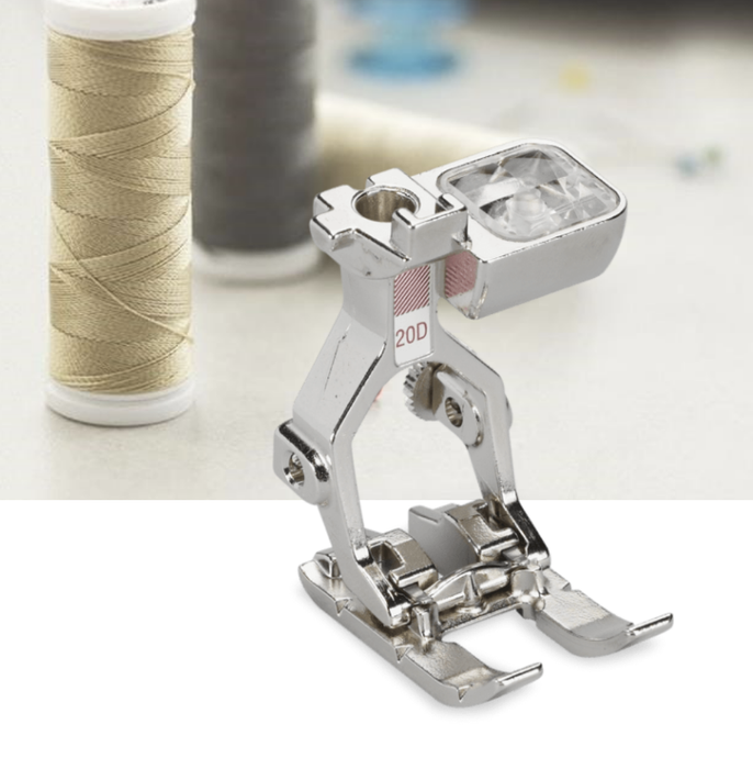 Bernina #20D Open Embroidery Presser Foot made of metal, displayed in front of spools of thread.