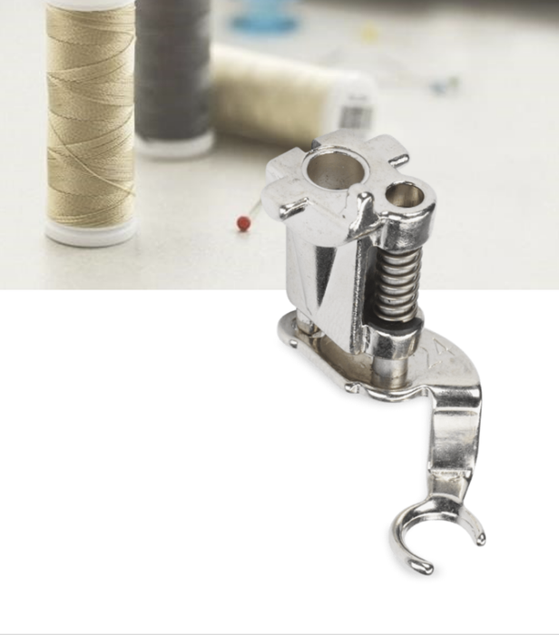 Bernina #24 Free-Motion Embroidery Presser Foot made of metal, displayed in a sewing environment with spools of thread in the background.