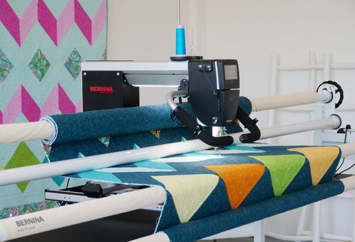 Bernina Q16 Plus on a studio frame machine with a colorful quilt on a table