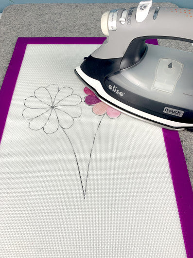 Gypsy Quilter appli-fuse mat with floral design and an iron on a gray surface