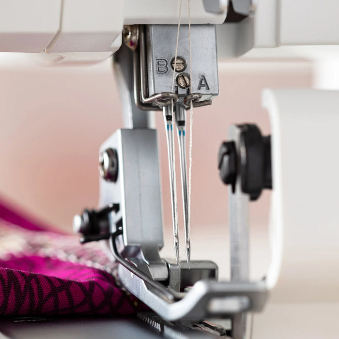 Close-up of a Schmetz serger needle size 90/14  and thread on a pink fabric background
