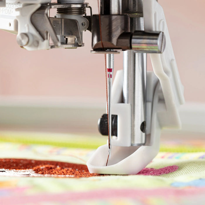 Close-up of a Schmetz sewing machine needle piercing fabric with a colorful background