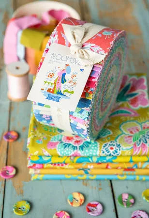 Bloomsville fabric collection jelly roll by Tilda laying on top of folded fabric with buttons